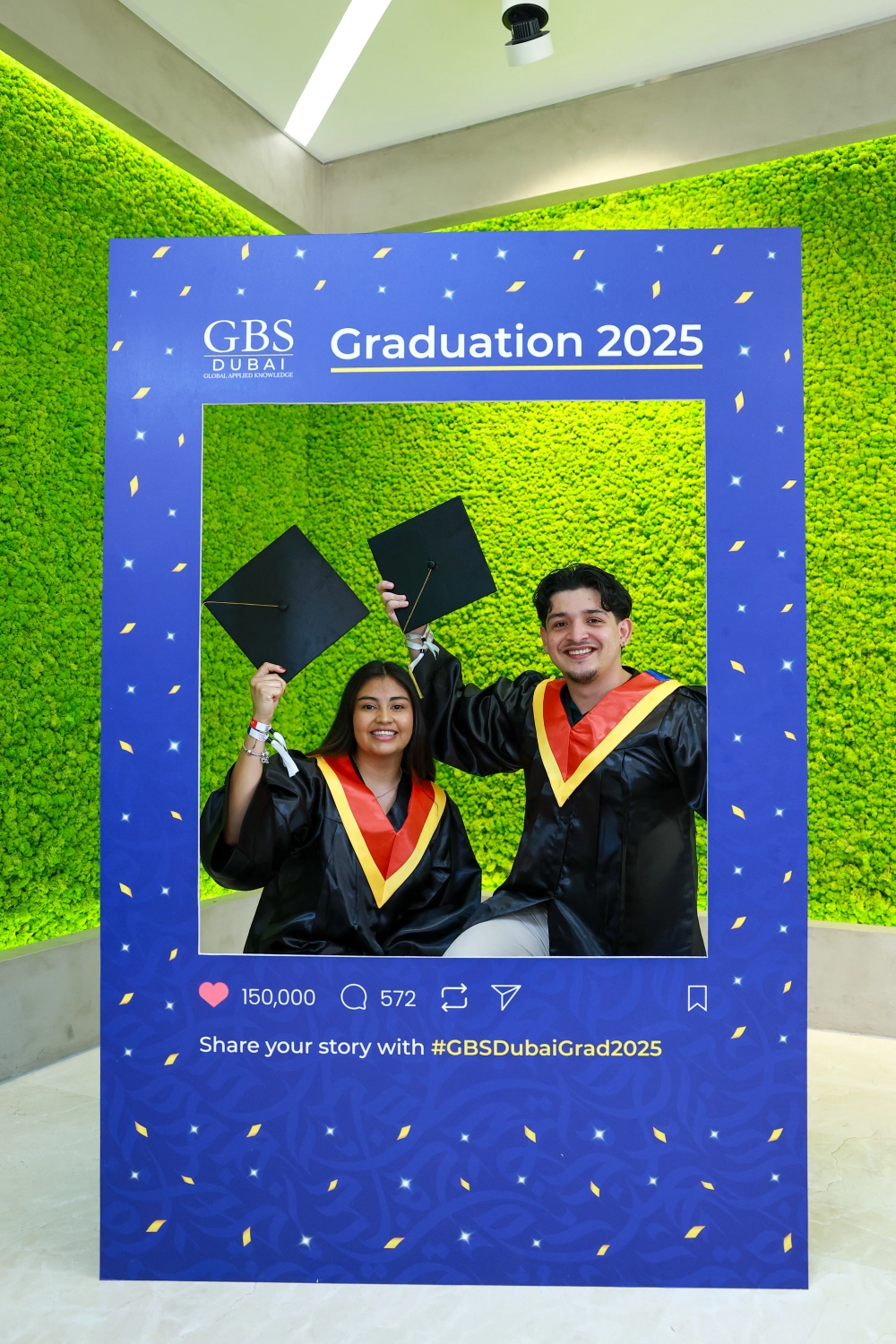 Two graduates posing in the graduation photo frame